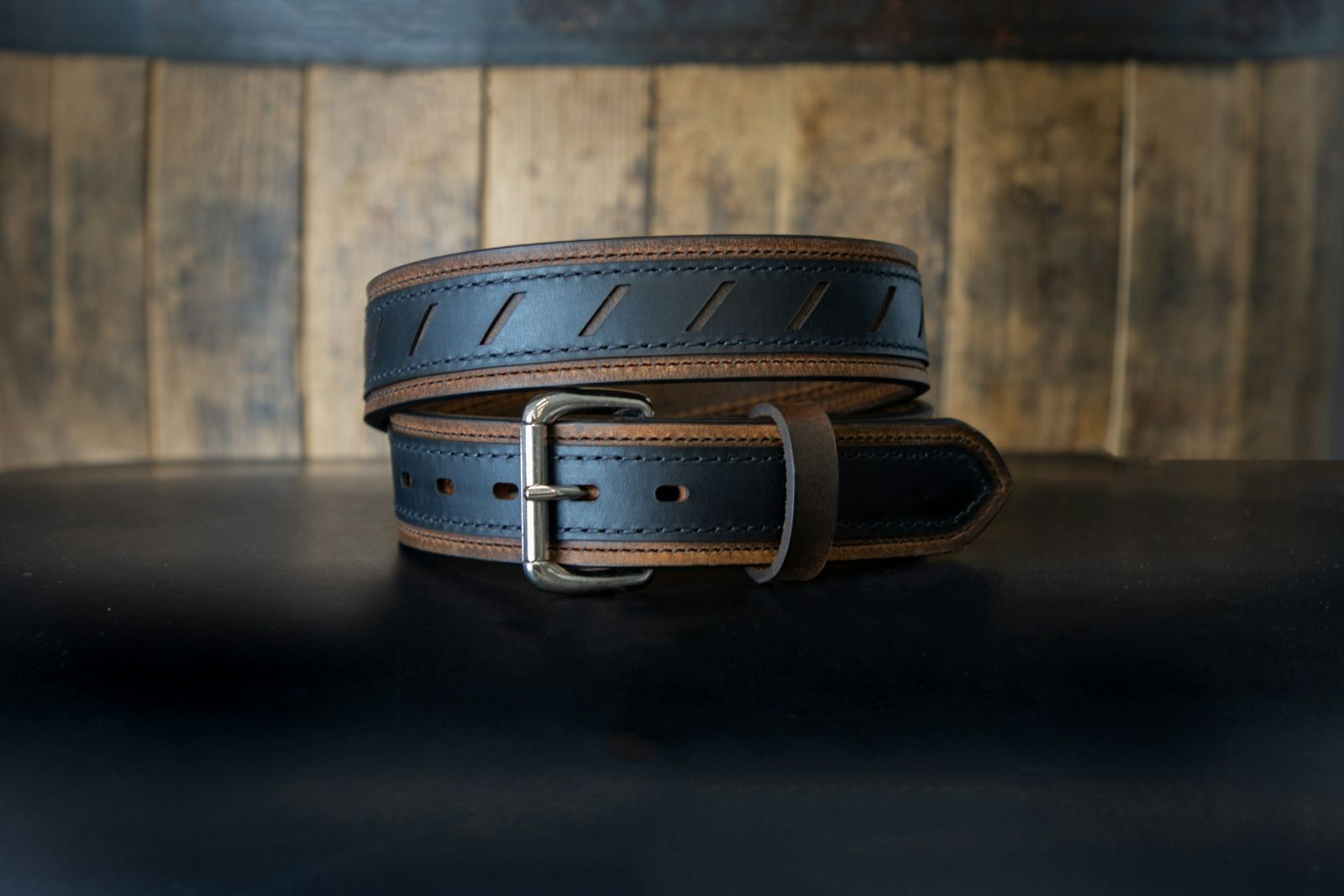 A conditioned handmade leather belt with brass buckle, showing the deepened color oils produce