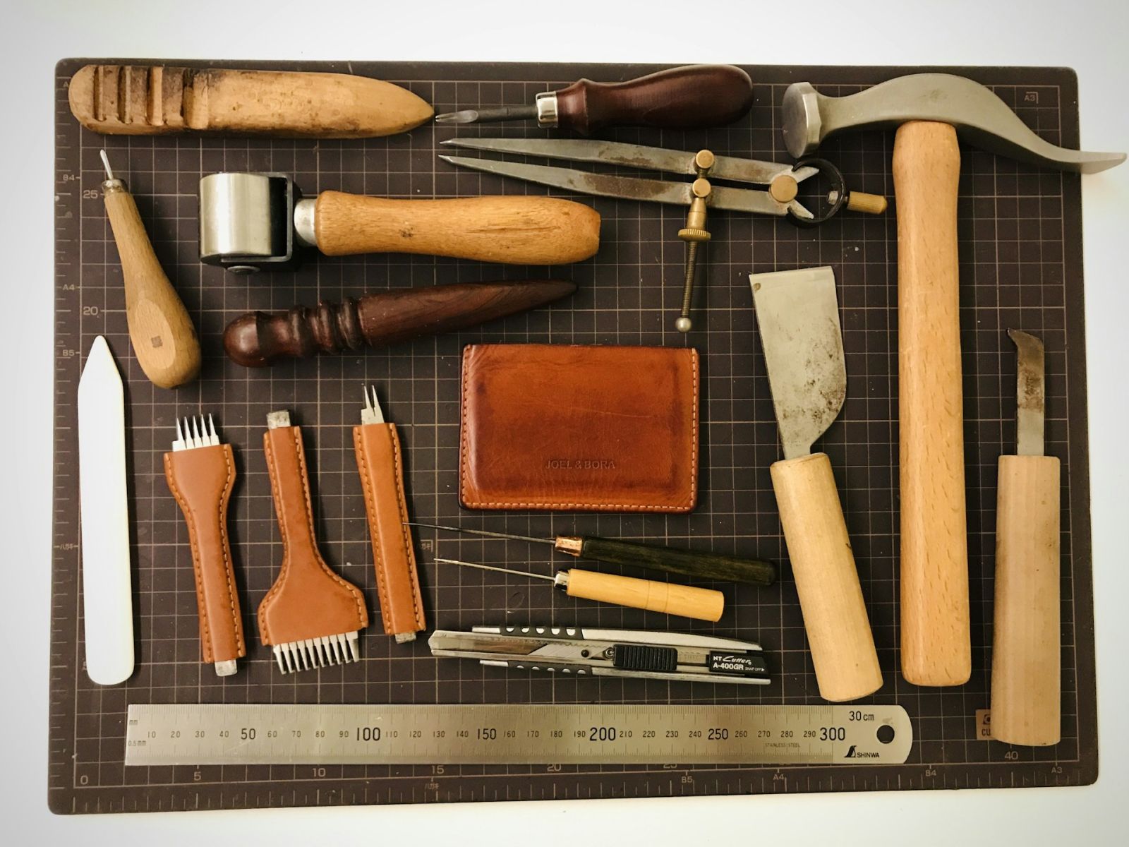 Leathercraft blades and tools laid out on a cutting mat — every one of them kept working by the strop