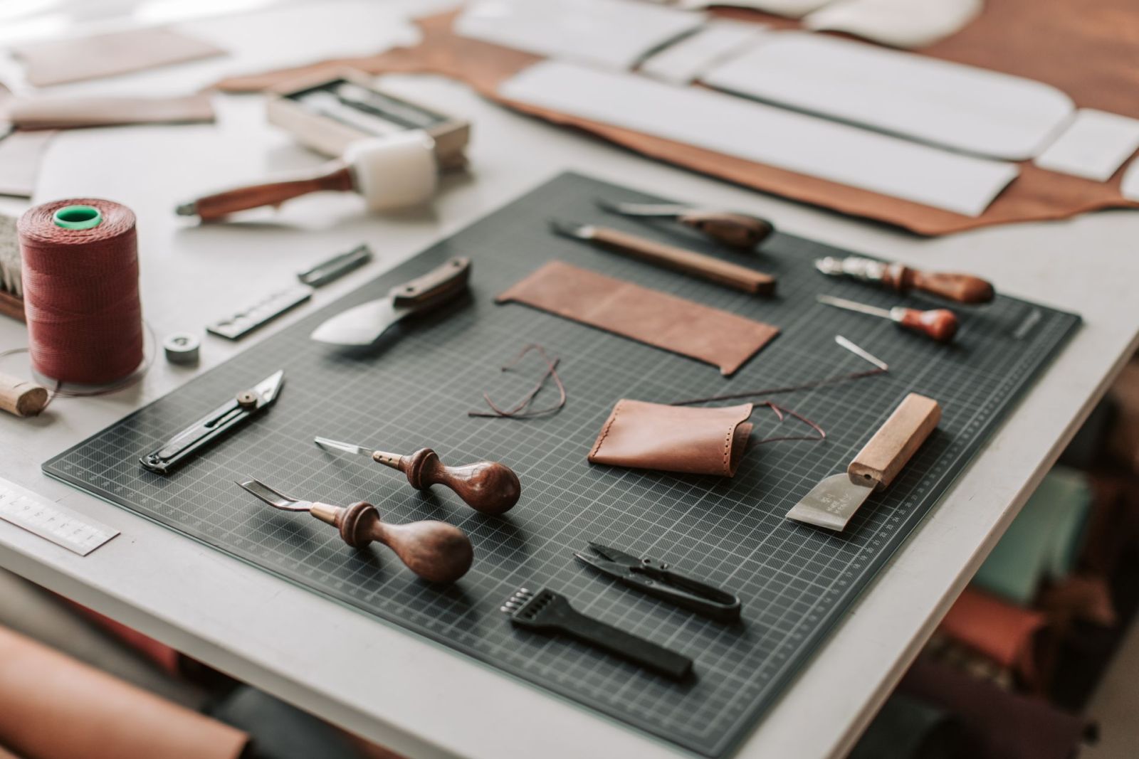 Leather knives, burnishers and hand tools on a cutting mat — all maintained with a strop and compound